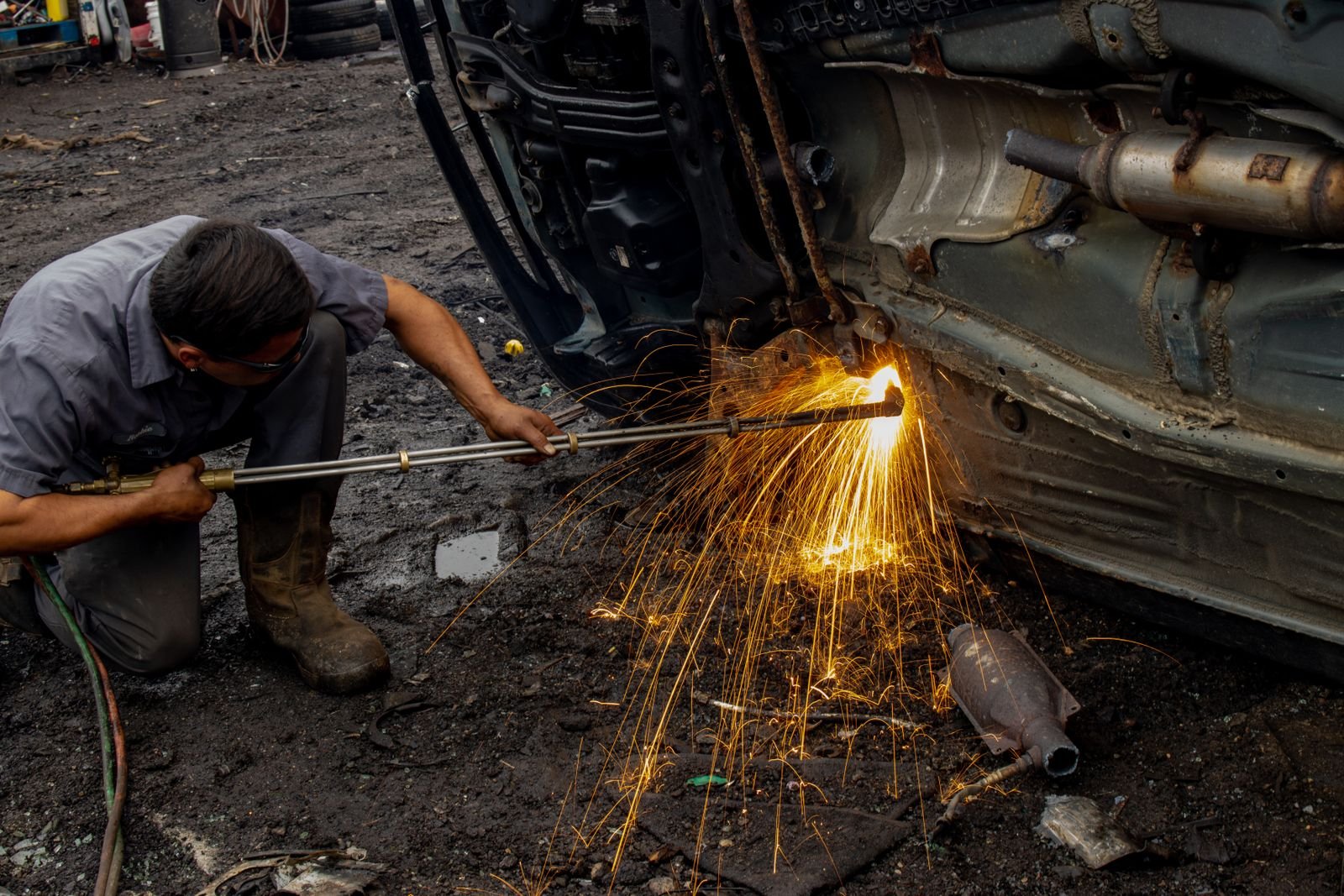 Mechanic repairing rust-damaged metal beneath a vehicle