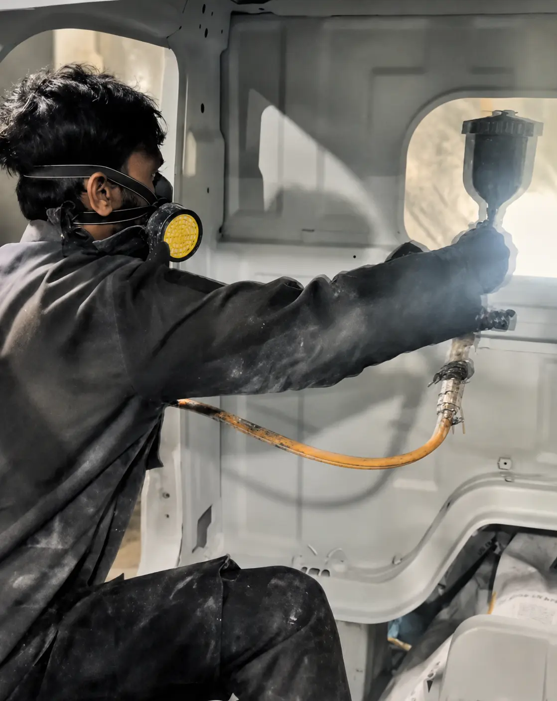 Painter applying protective coating inside a vehicle body